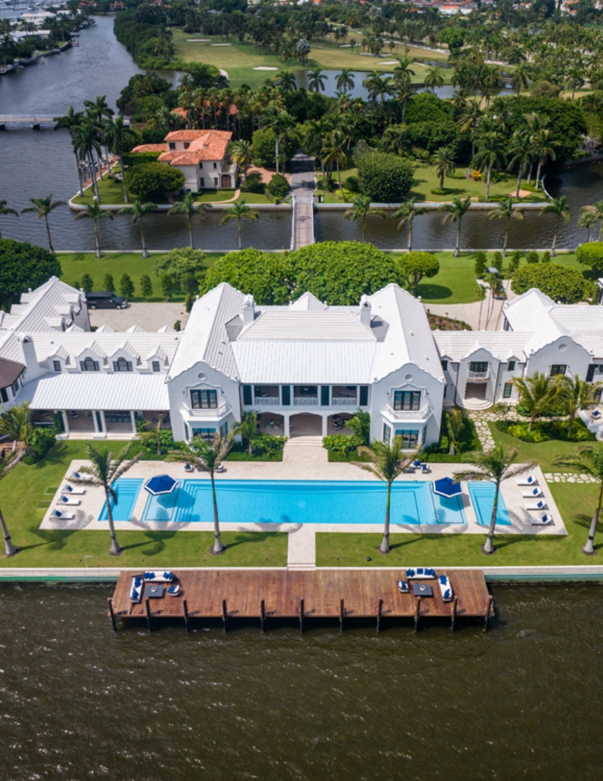 Aerial shot of an elegant mansion with a stunning pool, showcasing luxury and sophisticated design